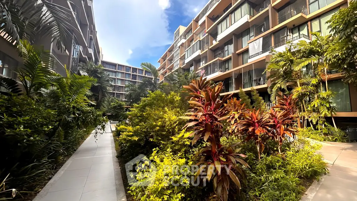 Modern residential building with lush garden and pathway, showcasing contemporary architecture and vibrant greenery.