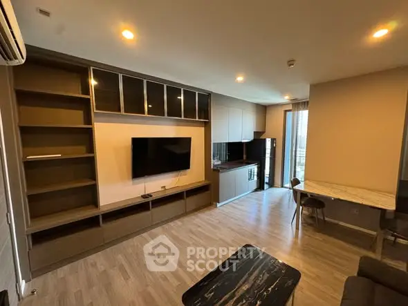 Modern living room with built-in shelves and open kitchen layout in a stylish apartment.