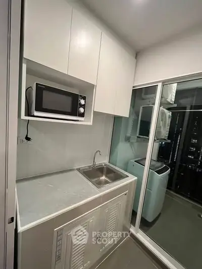 Compact modern kitchen with microwave and washing machine in sleek apartment