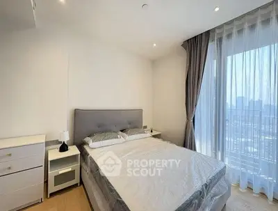 Modern bedroom with city view, featuring a cozy bed and elegant curtains, perfect for urban living.