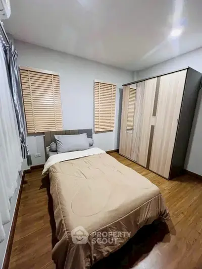 Cozy bedroom with wooden flooring and modern wardrobe in a stylish apartment.