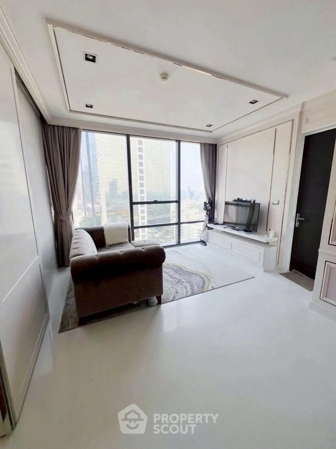 Modern living room with city view, featuring sleek furniture and large windows.