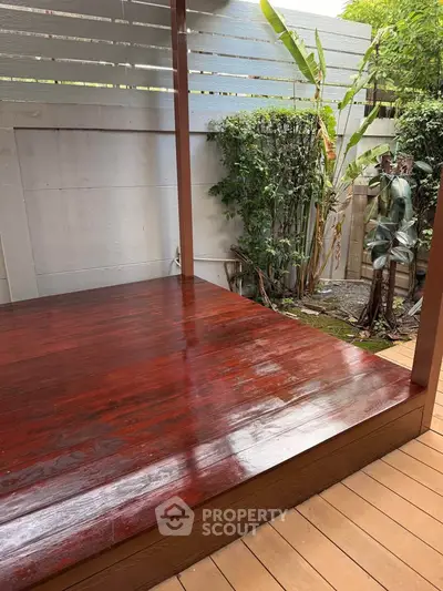 Beautifully polished wooden deck with lush greenery, perfect for outdoor relaxation.