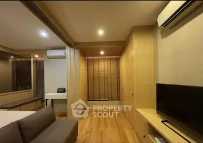 Modern living room with wooden flooring, air conditioning, and built-in storage cabinets.
