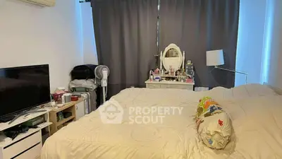 Cozy bedroom with modern decor and ample natural light, featuring a comfortable bed and stylish vanity.