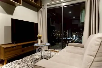 Modern living room with city view, featuring a cozy sofa, large TV, and stylish decor.