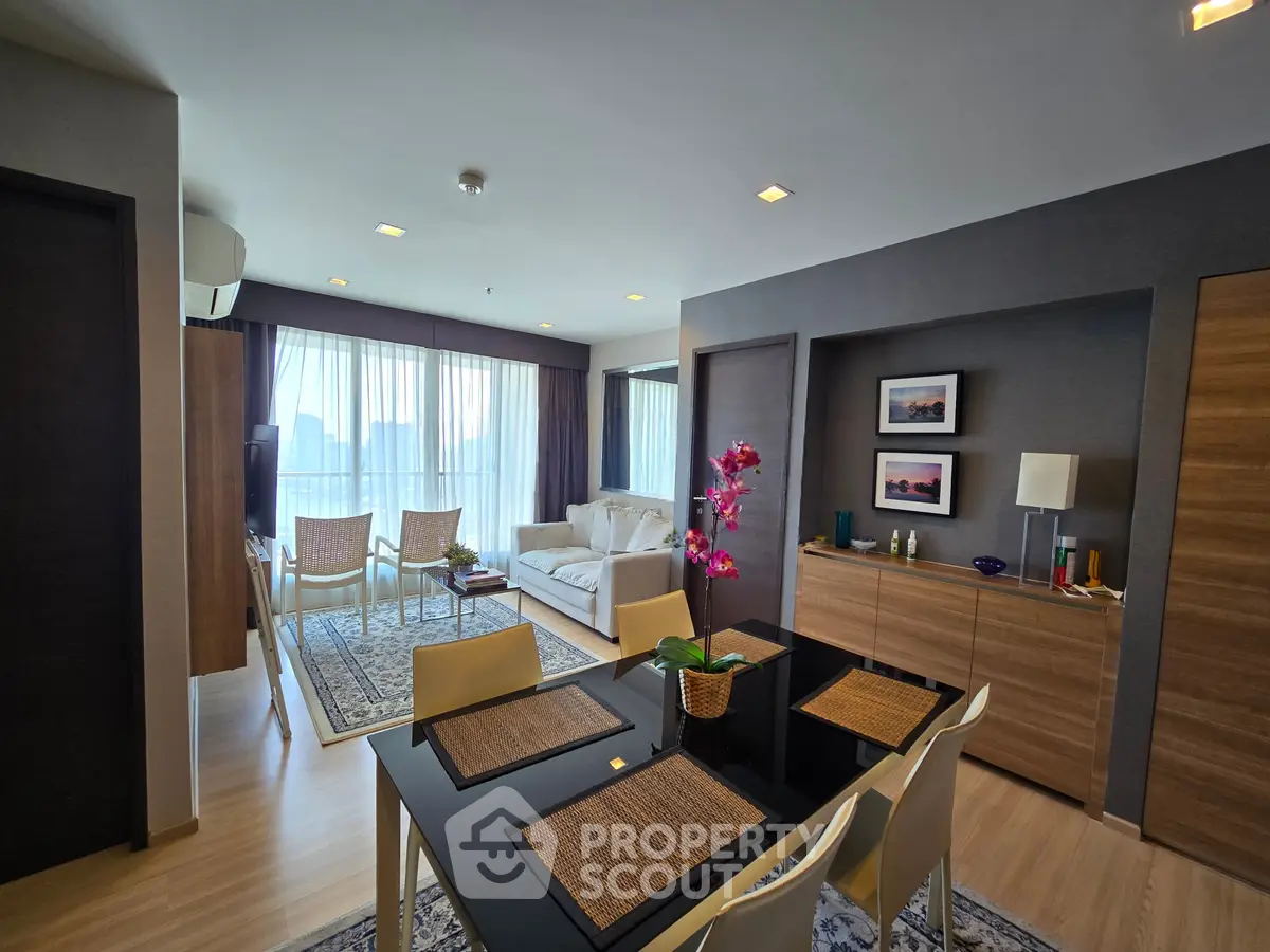 Spacious modern living room with elegant dining area and large windows offering natural light.
