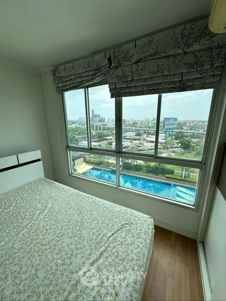 Cozy bedroom with large window offering stunning city and pool view, perfect for urban living.