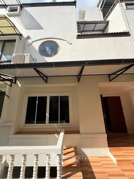 Charming townhouse exterior with unique round window and modern design.