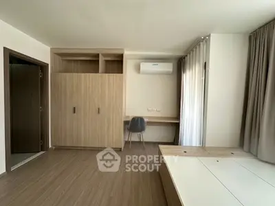 Modern bedroom with built-in wardrobe and desk, featuring sleek wooden flooring and air conditioning.