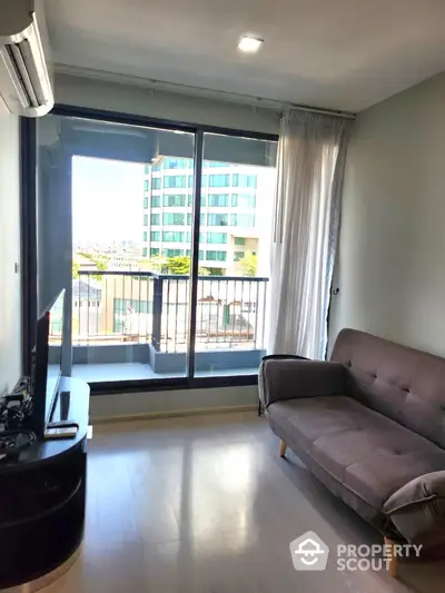 Modern living room with large window and city view, featuring a stylish sofa and sleek TV setup.