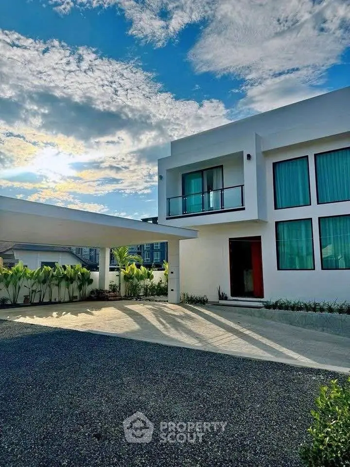 Modern luxury home with sleek architecture and spacious driveway under a vibrant sky.