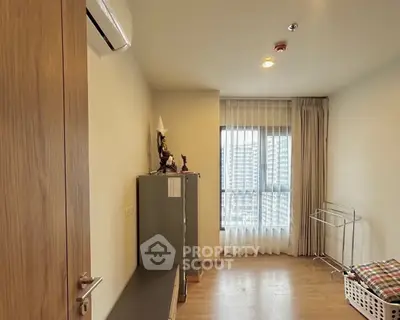 Spacious bedroom with large window and wooden flooring in modern apartment