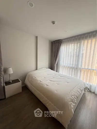 Cozy bedroom with natural light and modern decor, featuring a comfortable bed and elegant curtains.