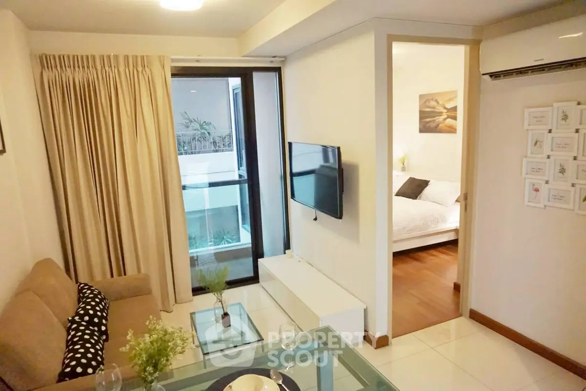 Modern living room with cozy sofa and wall-mounted TV, adjacent to a bright bedroom with balcony view.