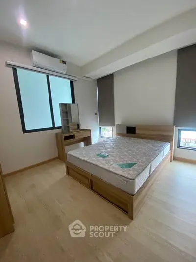 Modern bedroom with minimalist design, featuring a comfortable bed and ample natural light.