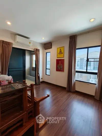 Spacious living room with wooden flooring and large windows in modern apartment.