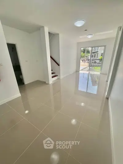 Spacious open-plan living area with glossy tiled floors and natural light, perfect for modern living.