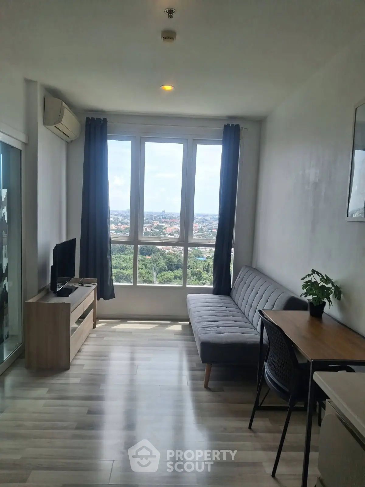 Bright living room with large windows and modern furniture offering a stunning city view.