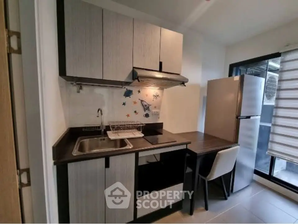 Modern compact kitchen with sleek cabinetry and stainless steel appliances in a cozy apartment.