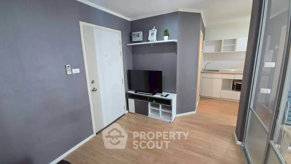 Modern living room with sleek TV setup and open kitchen layout, perfect for urban living.