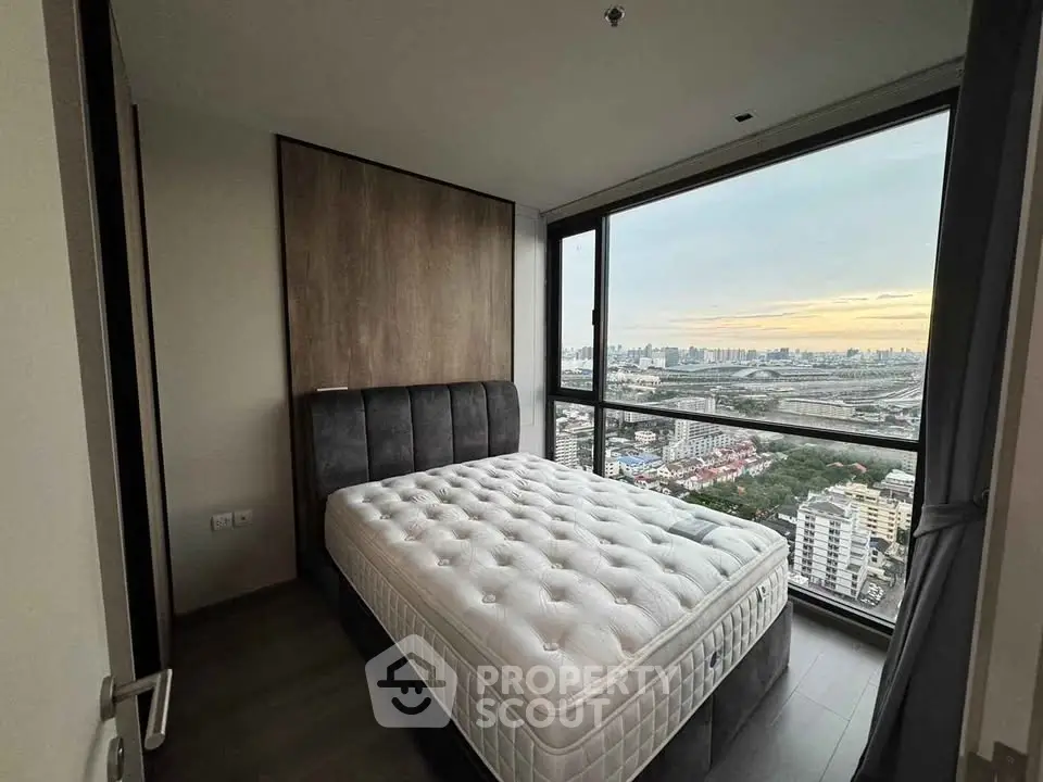 Modern bedroom with stunning city view and large window, featuring a cozy bed and elegant decor.