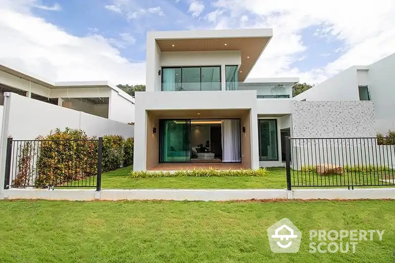 Modern two-story house with large windows and lush green lawn