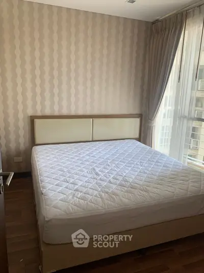 Cozy bedroom with large window and modern wallpaper, perfect for natural light lovers.