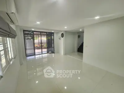 Spacious modern living room with large windows and sleek tile flooring, perfect for natural light and comfort.