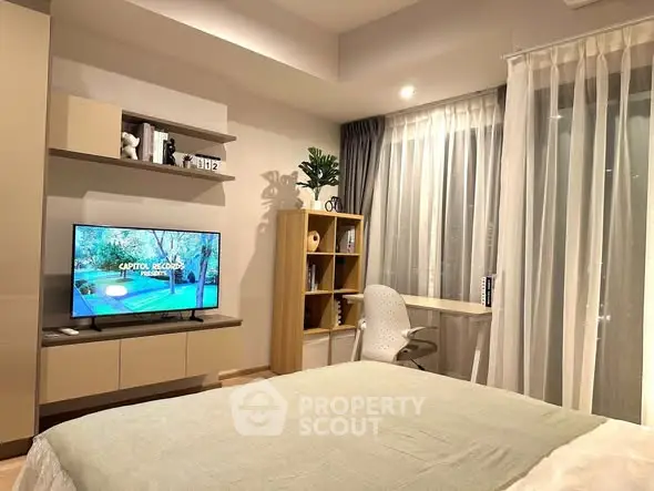 Modern bedroom with stylish decor and natural light, featuring a cozy bed, TV, and study area.