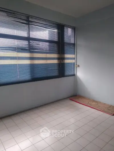 Spacious room with large window and tiled floor, perfect for customization.