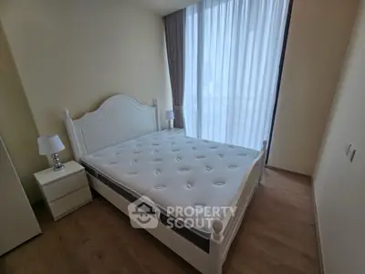 Spacious bedroom with large window and elegant white bed