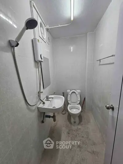 Compact bathroom with shower, sink, and toilet in a minimalist design.