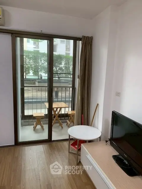 Cozy living room with balcony access, featuring a TV and modern decor, perfect for relaxation.