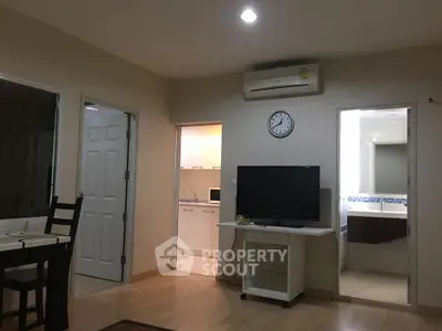 Cozy living room with TV, dining area, and view into kitchen and bathroom.