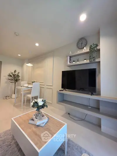 Modern living room with sleek furniture and dining area, featuring a wall-mounted TV and stylish decor.