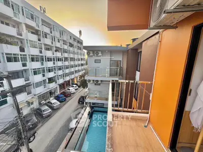 Modern urban balcony with pool view and vibrant cityscape at sunset