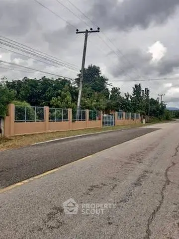 Scenic roadside view with fenced property and lush greenery