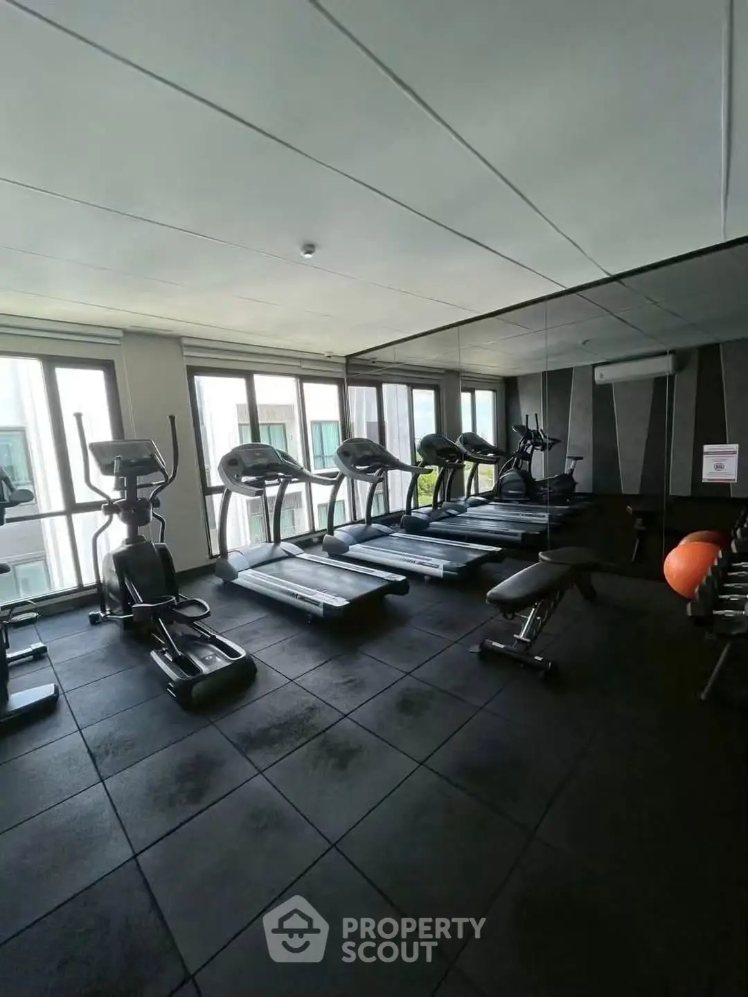 Modern gym with state-of-the-art equipment and large windows in a luxury residential building.