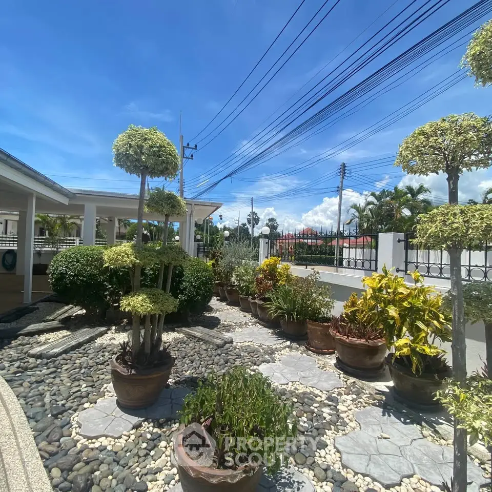 Beautifully landscaped garden with potted plants and stone pathway under a clear blue sky.