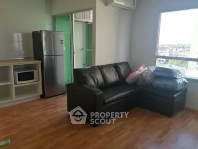Modern living room with black sofa and kitchen appliances in open layout apartment