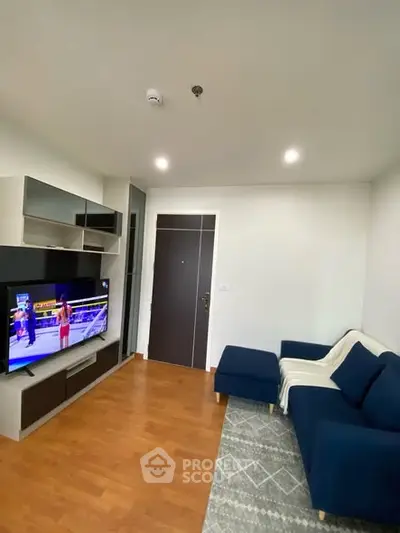 Modern living room with stylish blue sofa and entertainment unit, featuring wooden flooring and cozy ambiance.