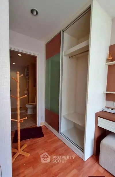 Modern apartment interior with wooden flooring, built-in closet, and bathroom view.