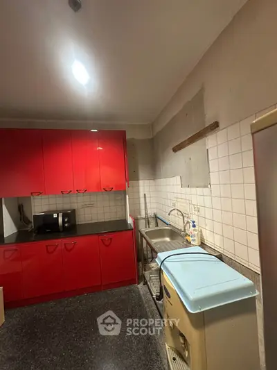 Cozy kitchen with vibrant red cabinets and modern appliances, perfect for culinary enthusiasts.