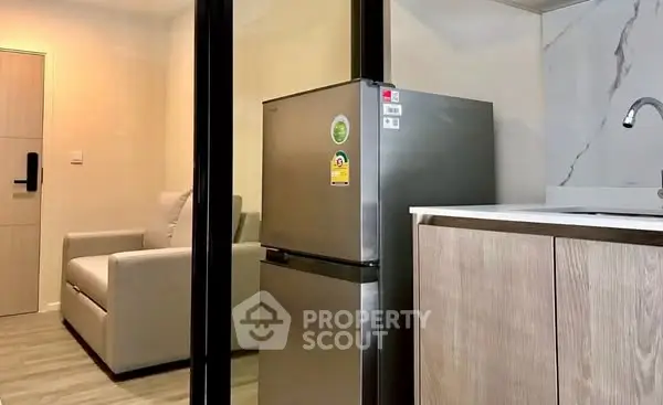 Modern compact kitchen with stainless steel fridge and cozy seating area.