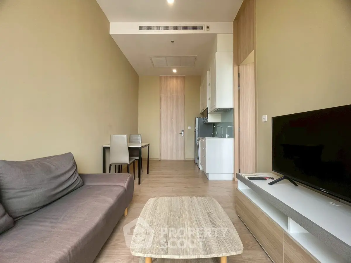 Modern living room with sleek furniture and open kitchen layout in a stylish apartment.