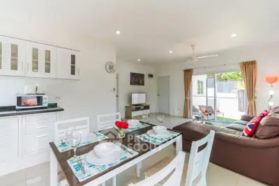 Spacious open-plan living room with modern kitchen and dining area, featuring bright natural light and stylish decor.