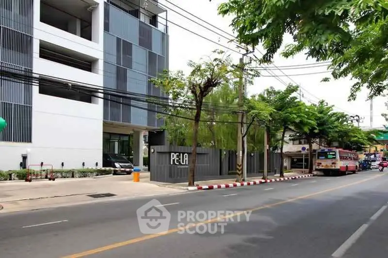 Modern building exterior with street view and lush greenery