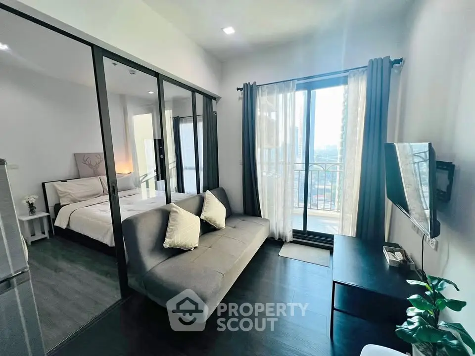 Modern apartment with open living room and bedroom, featuring large windows and balcony access.