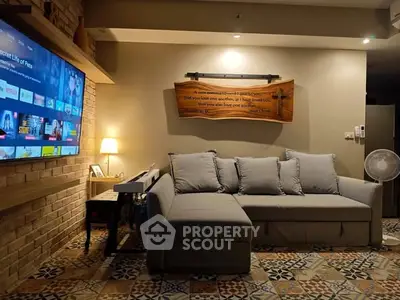 Cozy living room with stylish sofa and large TV, perfect for relaxation and entertainment.